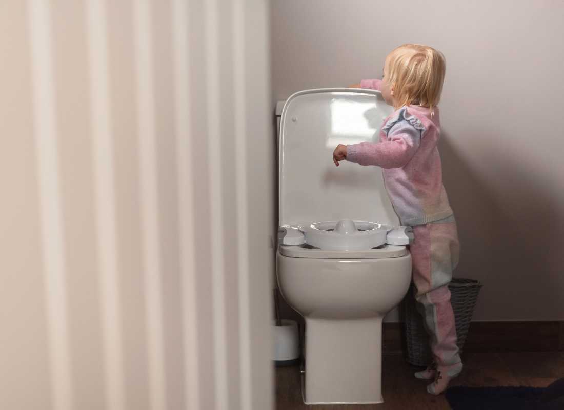 Toddler flushes the toilet with a Potette 2 in 1 on it